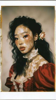 a woman with freckles on her face and long black hair wearing a red dress