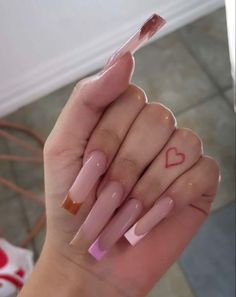 two hands with pink and orange nail polish holding a heart shaped sticker on their fingers