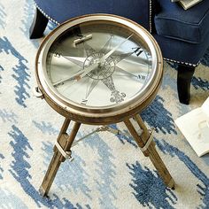 a small table with a clock on top of it next to a blue chair and ottoman