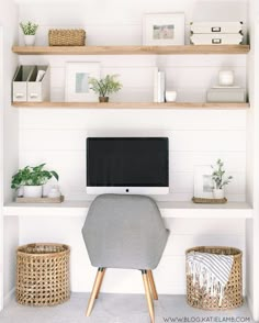 a computer monitor sitting on top of a wooden shelf next to baskets and plants in front of it