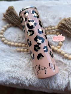 a pink and black leopard print water bottle with the words stay wild written on it