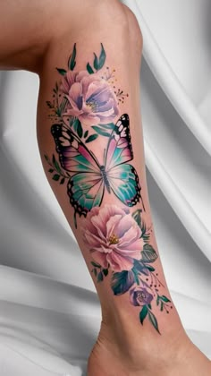 a woman's leg with flowers and butterflies on it, as well as a butterfly tattoo