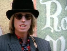 a man wearing a hat and sunglasses standing in front of a wall