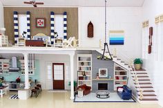 a doll house with furniture and accessories on the floor in front of a staircase leading up to a second story