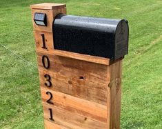 a wooden mailbox sitting on top of a lush green field