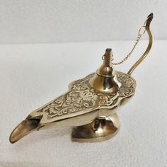 a brass bird figurine on a white surface with a chain hanging from it's neck