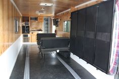 the inside of an rv with black furniture and wood paneling on the walls,