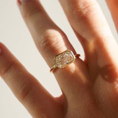 a woman's hand with a gold ring on it and a diamond in the middle