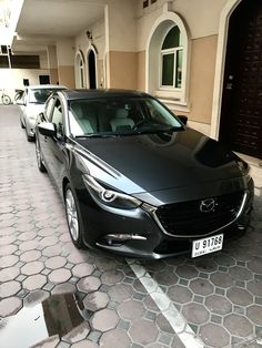 a black car is parked in front of a building with two cars on the street