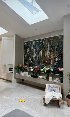 a living room with a large painting on the wall and flowers in vases next to it