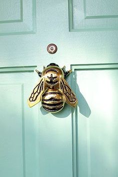 a gold bee door knocker on a green door