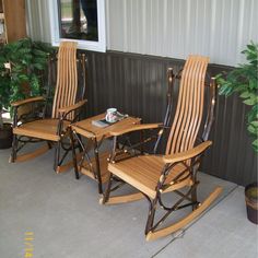 three wooden rocking chairs sitting on top of a porch next to a potted plant