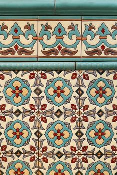 an ornate tile design on the side of a building with blue and red accents,