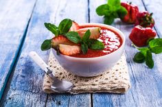 a bowl of soup with strawberries and mint