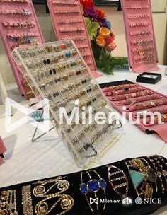 a table topped with lots of jewelry on display in front of pink wall - mounted mirrors