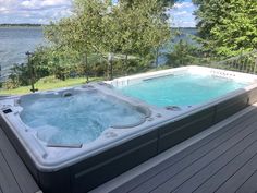 a hot tub sitting on top of a wooden deck next to a body of water