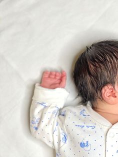 a baby laying on top of a white sheet