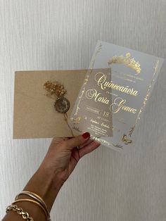 a woman holding up a wedding card with gold foil on the front and back side