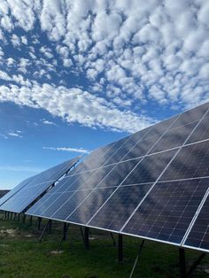 two rows of solar panels under a cloudy blue sky