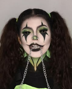 a woman with long hair and green makeup is wearing a chain around her neck as she looks at the camera