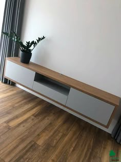 a plant sitting on top of a wooden shelf next to a window