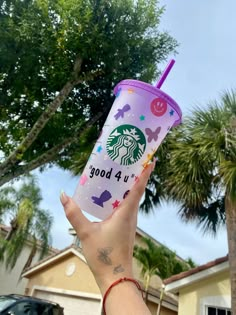 a person holding up a starbucks cup in front of a house