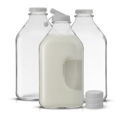 three glass bottles with milk in them on a white background