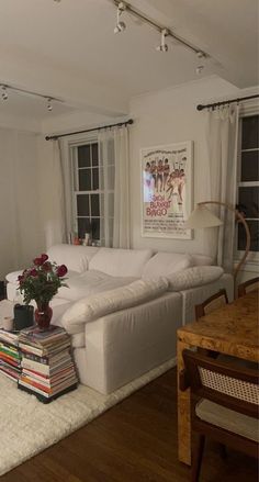 a living room filled with furniture and lots of books on top of a wooden floor