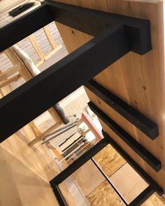 an overhead view of a wooden staircase with black railings and wood flooring in the background