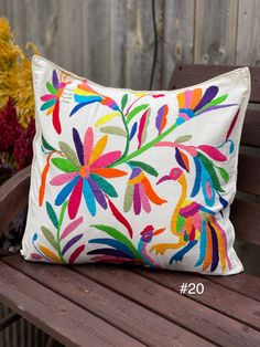 a colorful pillow sitting on top of a wooden bench