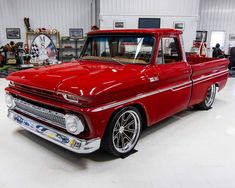 an old red pickup truck parked in a garage