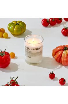 tomatoes, tomatoes and other vegetables are arranged around a candle