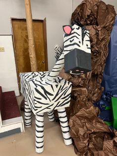 a cardboard zebra standing next to a pile of paper mache wrapped in brown and white