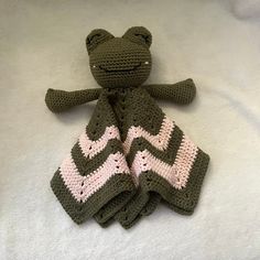 a crocheted frog sitting on top of a blanket