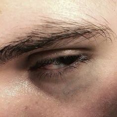 the eye of a man with black hair and white eyeshade, looking straight ahead