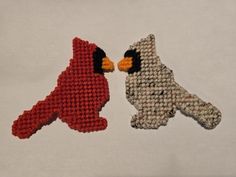 two birds made out of knitted material sitting next to each other on a white surface