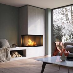 a living room filled with furniture and a fire place next to a large glass window