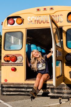 a woman sitting in the doorway of a school bus with her legs up and smiling