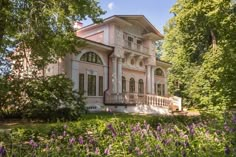 an old pink house surrounded by trees and flowers