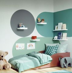 a child's bedroom with blue and green walls, teddy bear on the floor