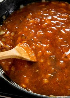 a wooden spoon in a pot filled with chili