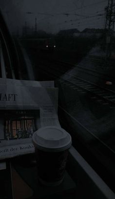 a cup of coffee sitting on top of a table next to a newspaper and train tracks