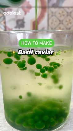 a glass filled with green liquid sitting on top of a counter