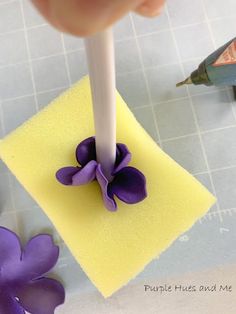 a person is using a pen to make a flower on a piece of yellow paper