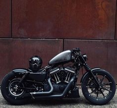 a black motorcycle parked in front of a brown building with a helmet on it's back tire