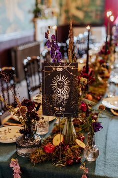 the table is set with flowers, candles and cards for guests to write on them