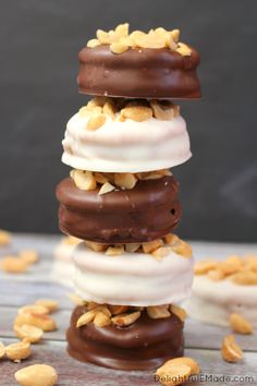 three chocolate covered donuts stacked on top of each other with nuts scattered around them