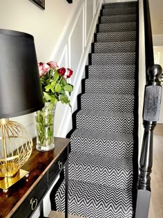 a black and white carpeted staircase leading up to a vase with flowers