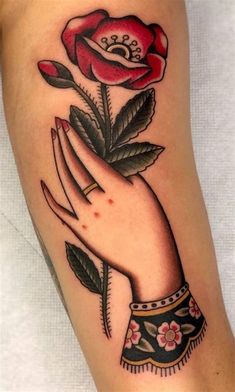 a woman's hand holding a rose tattoo on her arm