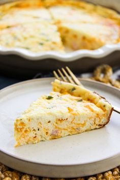 a slice of quiche on a plate with a fork in front of the pie